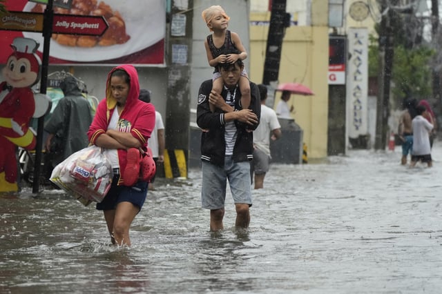 Residents wade along a flooded road as intense rains continue due to the southwest monsoon at Malabon city, Philippines on Thursday, July 24, 2025. (AP Photo/Aaron Favila)