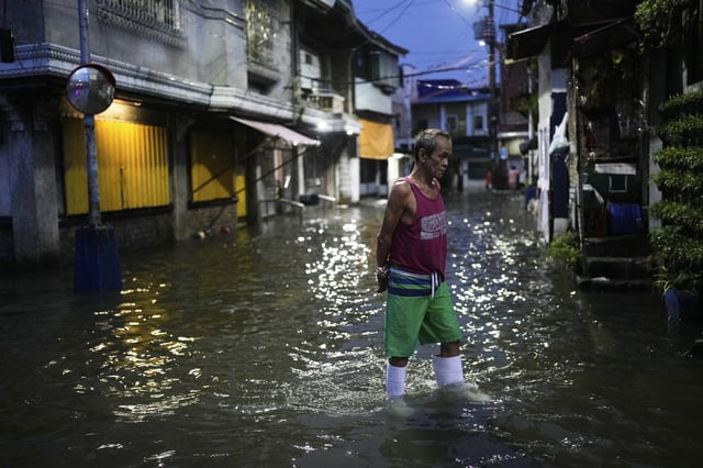 A man walks along a flooded road as intense rains continue due to the southwest monsoon at Malabon city, Philippines on Thursday, July 24, 2025. (AP Photo/Aaron Favila)