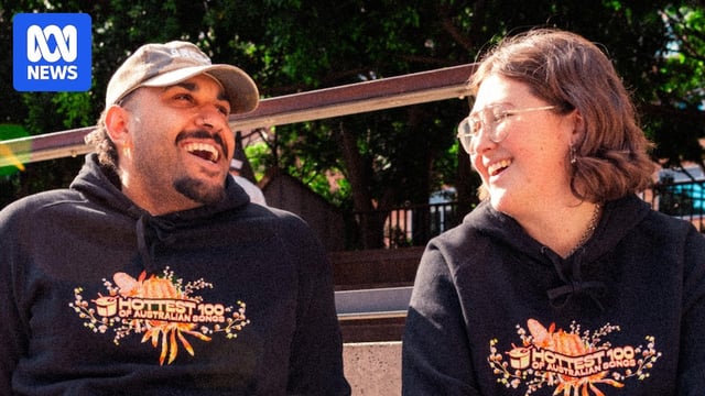 triple j's Abby & Tyrone wearing Hottest 100 of Australian songs merch laughing together