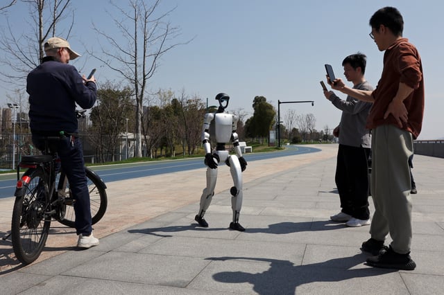 Passersby film a Unitree G1 humanoid robot operated by a staff member, in between Unitree's demonstrations to Reuters, at a park in Hangzhou, Zhejiang province, China March 21, 2025. REUTERS/Florence Lo/File Photo