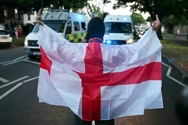 Un manifestant enveloppé dans le drapeau anglais lors d'un rassemblement anti-migrants à Epping, au nord-est de Londres, le 20 juillet 2025