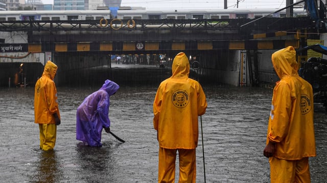 Municipal workers check water level on a flooded road during rain at Andheri subway in Mumbai.