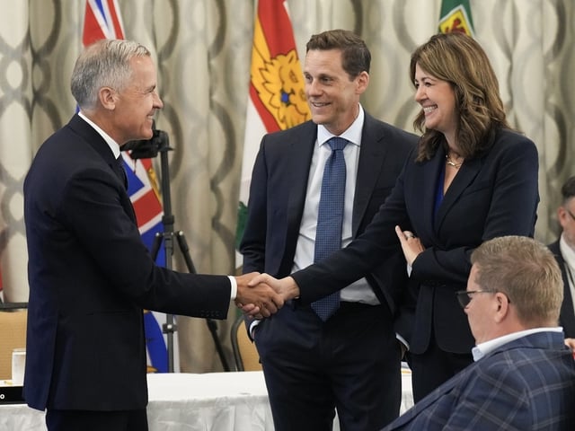 Canadian Prime Minister Mark Carney, left, greets Alberta Premier Danielle Smith, right, during the 2025 summer meetings of Canada's Premiers at Deerhurst Resort in Huntsville, Ont., on Tuesday, July 22, 2025.