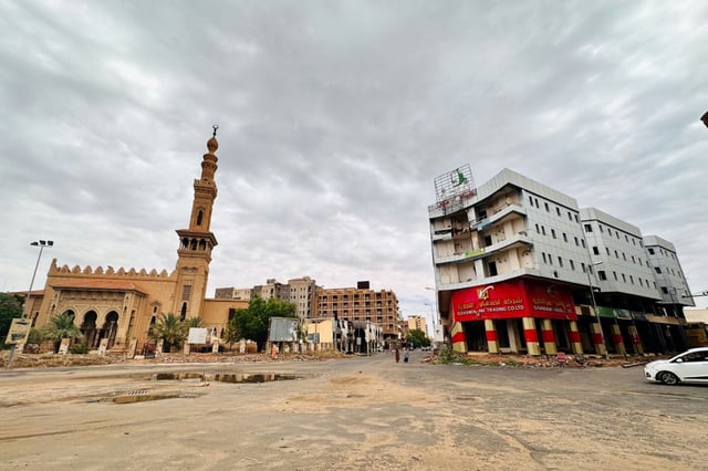 People walk amid damaged buildings at al-Hurriya street in Khartoum, which was recaptured by the army in March