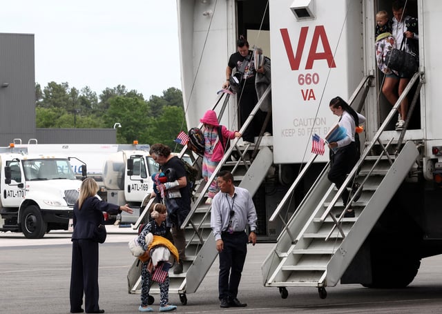 The first group of white South African refugees step from a "people mover" upon arrival at Dulles International Airport in Dulles, Virginia, U.S., May 12, 2025. REUTERS/Kevin Lamarque/File Photo