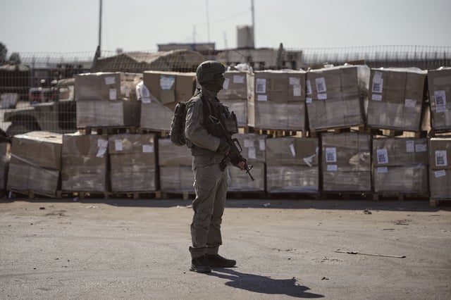 FILE - An Israeli soldier stands beside humanitarian aid packages awaiting pickup on the Palestinian side of the Kerem Shalom crossing in the Gaza Strip, Thursday, July 24, 2025, during a media tour organized by the Israeli army. (AP Photo/Ohad Zwigenberg, file)