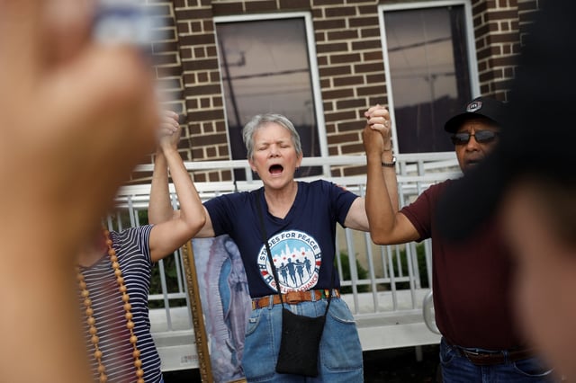 Celine Woznica, holds hands with others, during a song for undocumented immigrants being transported from the U.S. Immigration and Customs Enforcement (ICE) Detention Center, as she participates in a weekly prayer group, in Broadview, Illinois., U.S., June 20, 2025. REUTERS/Octavio Jones