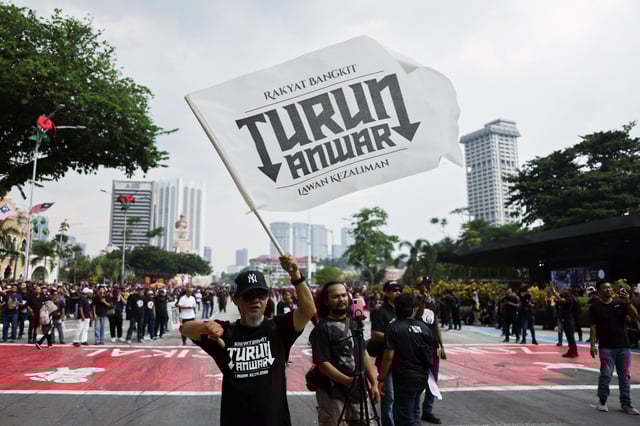 A man waves a flag written with the slogan 'TURUN ANWAR', which means 'Step down, Anwar', during a protest calling for Malaysian Prime Minister Anwar Ibrahim to resign in Kuala Lumpur, Malaysia July 26, 2025. REUTERS/Hasnoor Hussain