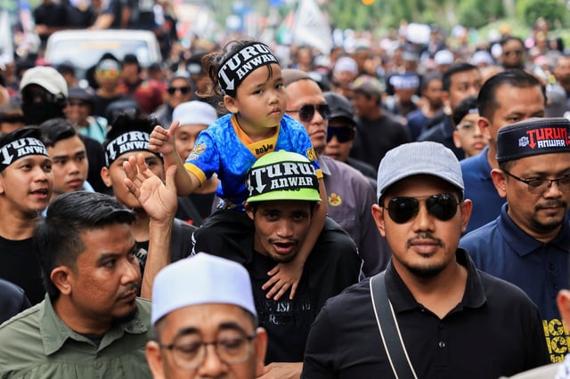 People wearing headbands with the slogan 'TURUN ANWAR', which means 'Step down, Anwar', march during a protest calling for Malaysian Prime Minister Anwar Ibrahim to resign in Kuala Lumpur, Malaysia July 26, 2025. REUTERS/Hasnoor Hussain