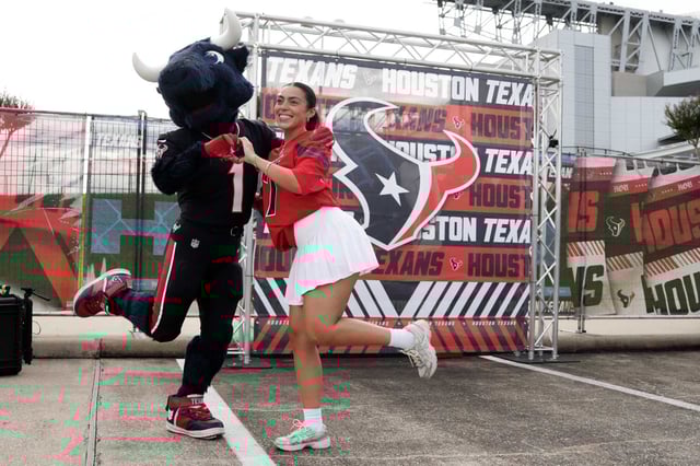 Julianna Ventura, right, poses of a photo with Houston Texans mascot Toro during an NFL training camp practice at Houston Methodist Training Center in Houston, Saturday, July 26, 2025.