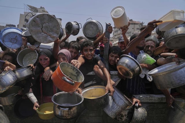 Palestinos intentan obtener comida en la Ciudad de Gaza.