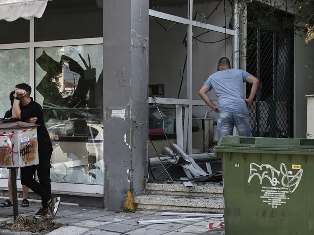 A man looks at a damaged shop following a strong blast in Thessaloniki on July 26, 2025. A strong blast early on July 26, 2025 damaged an apartment building in a suburb of Greece's second city Thessaloniki, wounding two passersby and shattering windows of nearby buildings. Six cars were also damaged in the explosion in the suburb of Sikies and anti-terror police were probing the incident, public broadcaster ERT said. (Photo by Sakis Mitrolidis / AFP) (Photo by SAKIS MITROLIDIS/AFP via Getty Images)