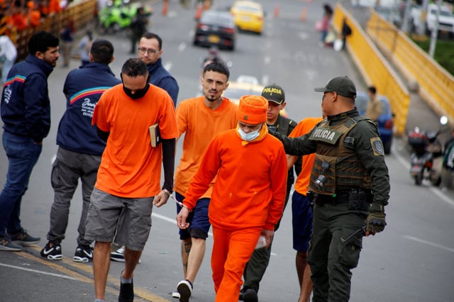 An Ecuadorian police officer walks with deported Colombians up at the Rumichaca International Bridge in Colombia, July 26, 2025. Colombian Foreign Ministry/Handout via REUTERS