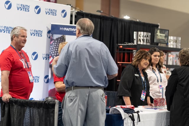 People talk at a booth for My Faith Votes in the sponsor hall as conservative leaders and personalities attend Turning Point USA's AmericaFest 2023 in Phoenix, Arizona, on December 16, 2023.