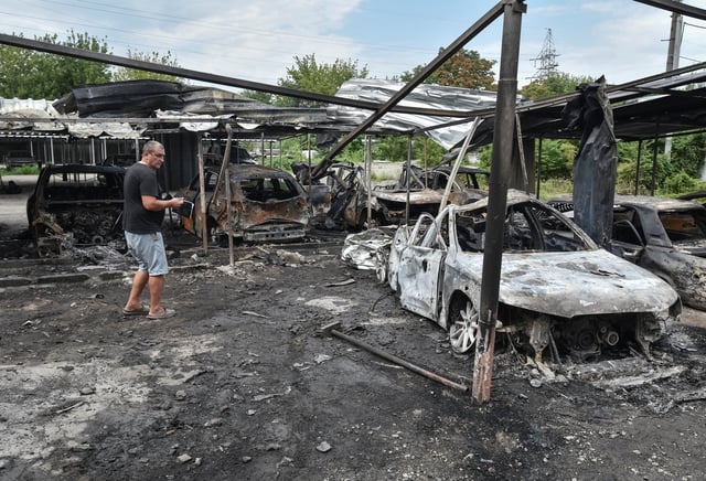 A resident stands next to burned cars at the site of a Russian drone strike, amid Russia's attack on Ukraine, in Dnipro, Ukraine July 26, 2025. REUTERS/Mykola Synelnykov