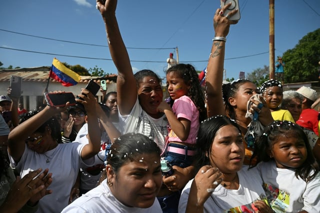 Mercedes Yamarte (C), mother of Mervin Yamarte, a Venezuelan migrant repatriated from a prison in El Salvador, reacts upon his arrival while holding Mervin's daughter in her arms