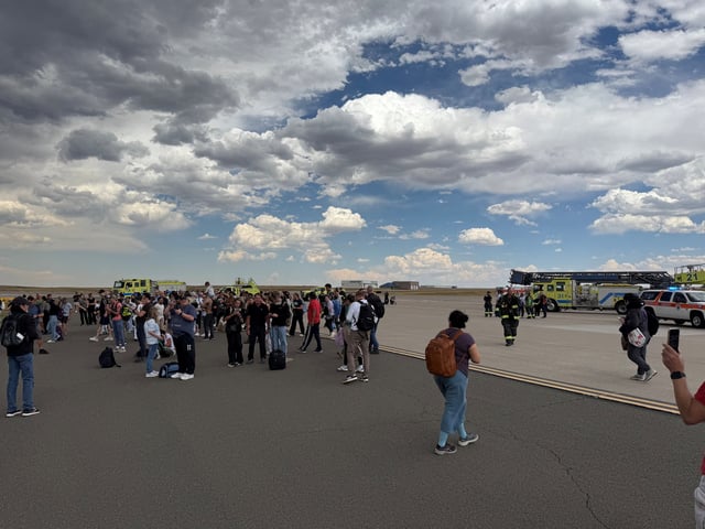 Passengers gather after evacuating an American Airlines plane that caught fire at Denver International Airport on July 26, 2025.