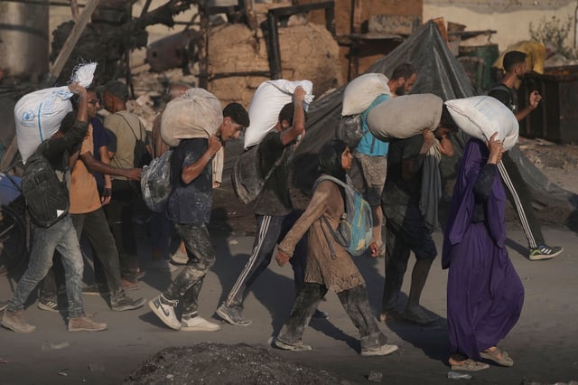 Palestinians carry sacks of flour unloaded from a humanitarian aid convoy that reached Gaza City from northern Gaza on Saturday, July 26, 2025.