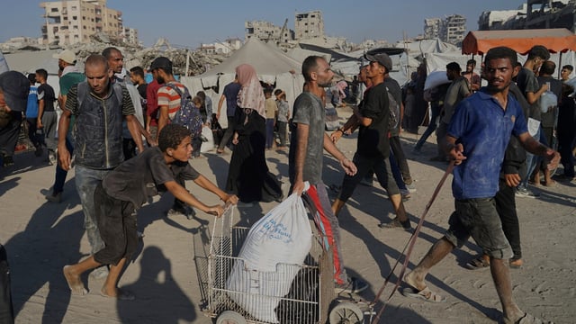 Palestinians carry sacks of flour unloaded from a humanitarian aid convoy that reached Gaza City from the northern Gaza Strip, Saturday, July 26, 2025. 