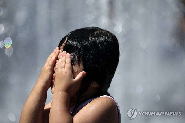 Children play in a fountain at Gwanghwamun Square in central Seoul amid hot weather on July 27, 2025. (Yonhap)