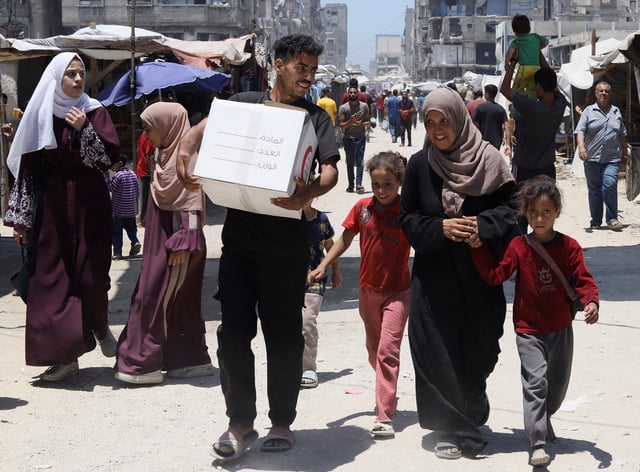 The son of displaced Palestinian woman Iman Suleiman, from Beit Lahiya, carries a box of aid the family received, distributed by the Emirates Red Crescent, in Gaza City, June 26, 2025. REUTERS/Khamis Al-Rifi/File Photo