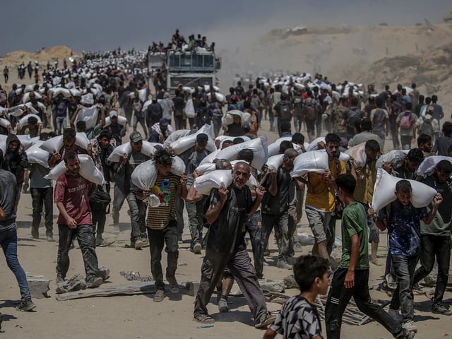 ZIKIM (-), 27/07/2025.- Internally displaced Palestinians carry bags of flour near a food distribution point in Zikim, northern Gaza Strip, 27 July 2025. The Israeli army declared a 'tactical pause' in military operations in parts of the Gaza Strip on 27 July, to facilitate the safe passage of humanitarian aid convoys. More than 130 Palestinians, the majority of whom children, have died of malnutrition in the Gaza Strip, the Palestinian Ministry of Health said on 27 July. EFE/EPA/MOHAMMED SABER