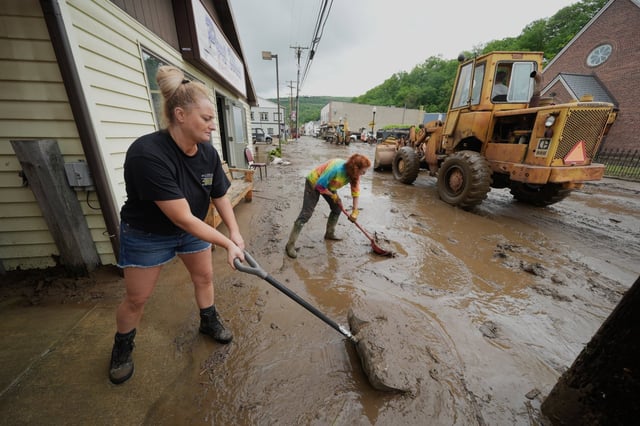 From left, Ashley Rishel from the Allegany County 911 and Lesley Moran help clean up Main Street after flooding on Wednesday, May 14, 2025 in Westernport, Md.