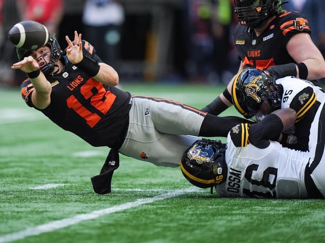  B.C. Lions quarterback Nathan Rourke (12) throws the ball away as Hamilton Tiger-Cats’ Julian Howsare (95) and Philip Ossai (46) nearly sack him during the first half