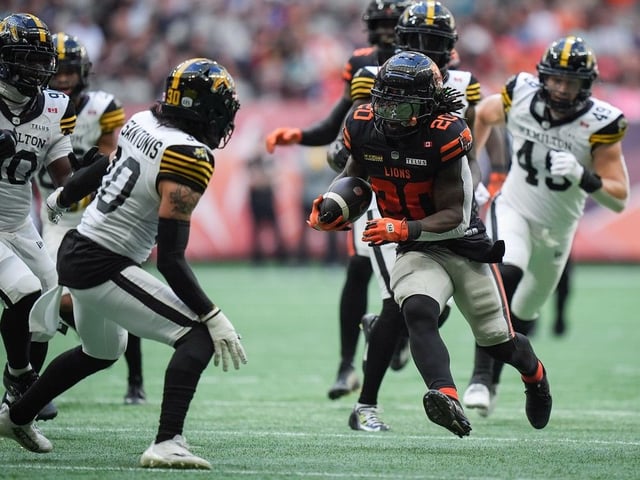  B.C. Lions’ James Butler (20) runs the ball past Hamilton Tiger-Cats’ Stavros Katsantonis (30) during the first half of a CFL football game, in Vancouver, on Sunday, July 27, 2025.