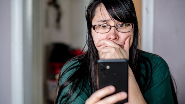 A woman looking at her phone with a concerned expression