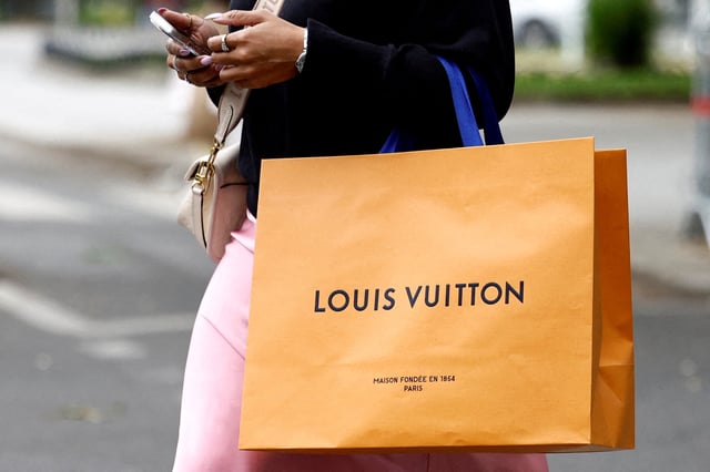 FILE PHOTO: A woman walks with a Louis Vuitton shopping bag in Paris, France, April 17, 2025. REUTERS/Abdul Saboor/File Photo