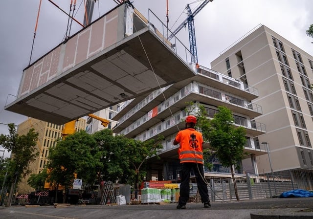 Operarios trabajando en la construcción de viviendas públicas en Barcelona construidas por módulos