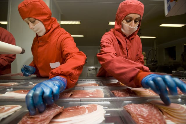 This stock image shows workers preparing luncheon meat.