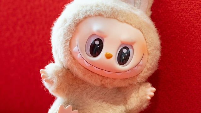 A plush Labubu doll against a red background.