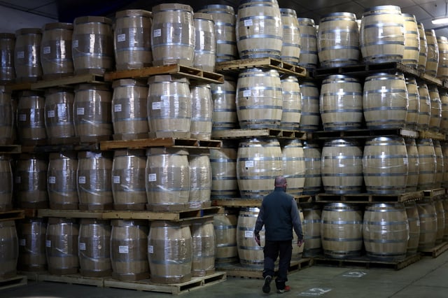 An employee walks past oak barrels at the Tonnelleries Vicard cooperage in Cognac, France, April 3, 2025. REUTERS/Stephane Mahe/File Photo