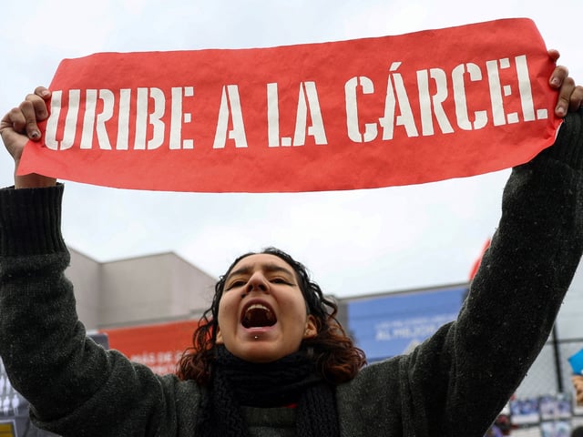 A person holds a banner reading "Uribe to jail", as people protest against former Colombian President Alvaro Uribe outside the Paloquemao court complex while waiting for the ruling in a criminal case against him, in Bogota, Colombia, July 28, 2025. REUTERS/Luisa Gonzalez
