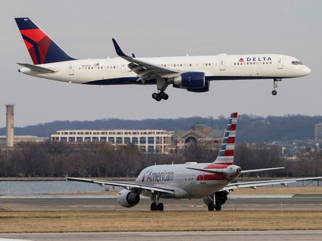 An American Airlines aircraft taxis as a Delta Air Lines aircraft lands at Reagan National Airport in Arlington, Virginia, U.S., January 24, 2022.   REUTERS/Joshua Roberts