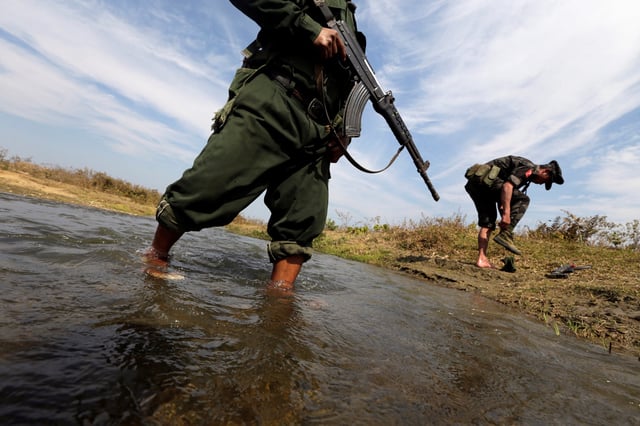 A soldier from the Kachin Independence Army (KIA) puts on his shoes as he and his comrade cross a stream towards the front line in Laiza, Kachin state, January 29, 2013. REUTERS/David Johnson/File Photo