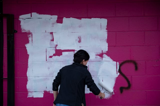 Bibiana Mesa paints over graffiti reading “ICE RULES” on July 20, 2025, after an overnight vandal tagged their grocery store, La Fruteria, for the second night in a row in the 2700 block of West Cermak Avenue in the Little Village neighborhood of Chicago. (Brian Cassella/Chicago Tribune)