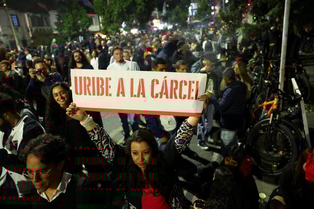 A woman holds a banner that reads "Uribe goes to prison", as people gather in celebration after a judge found former Colombian President Alvaro Uribe guilty of abuse of process and bribery of a public official, in Bogota, Colombia July 28, 2025. REUTERS/Luisa Gonzalez