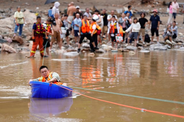 Un homme est évacué dans un bateau en plastique après de fortes pluies qui ont inondé la région, dans le district de Huairou, à Pékin, le 28 juillet 2025.