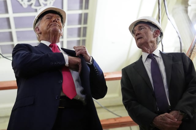 President Donald Trump, left, reaches for a document of cost figures as Federal Reserve Chairman Jerome Powell watches during a visit to the Federal Reserve, Thursday, July 24, 2025, in Washington. (AP Photo/Julia Demaree Nikhinson)
