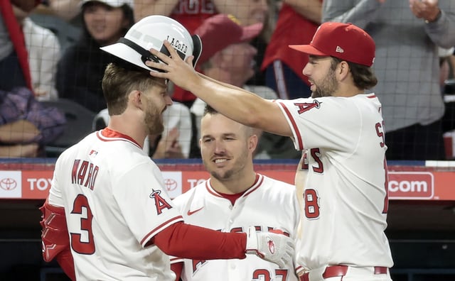 The Angels’ Taylor Ward, left, celebrates with teammates Nolan Schanuel, right, and Mike Trout as he returns to the dugout after hitting a go-ahead home run during the sixth inning of their game against the Texas Rangers on Monday night at Angel Stadium. (Photo by Ronald Martinez/Getty Images)