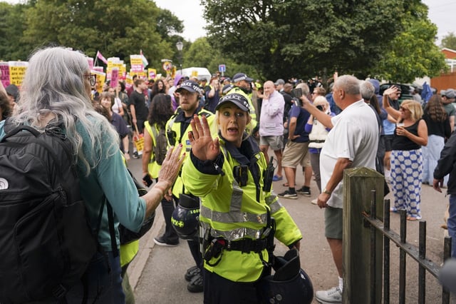 A police officer reacts as demonstrators hold placards and banners as they leave a protest outside the Bell Hotel in Epping, near London, Sunday, July 27, 2025.(AP Photo/Alberto Pezzali)