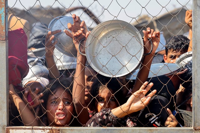 TOPSHOT - Palestinians, mostly children, push to receive a hot meal at a charity kitchen in the Mawasi area of Khan Yunis in the southern Gaza Strip on July 22, 2025. The head of Gaza's largest hospital said 21 children have died due to malnutrition and starvation in the Palestinian territory in the past three days, amid a devastating assault by Israeli forces. (Photo by AFP) (Photo by -/AFP via Getty Images)          