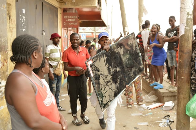 Un homme transporte un écran de télévision, alors que des pillages ont lieu en marge des manifestations liées à la grève des taxis à Luanda, capitale de l'Angola le 28 juillet 2025