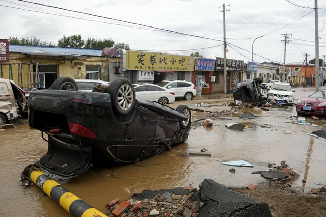 Umgestürzte Autos liegen nach heftigen Regenfällen in und um die chinesische Hauptstadt auf einer Straße im Pekinger Bezirk Miyun.