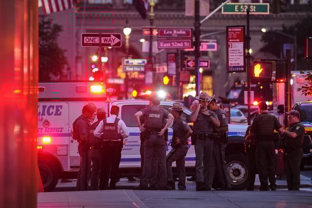 New York State Police troopers gather on 52nd Street outside a Manhattan office building where at least five people were shot, including a New York City police officer, in New York City on July 28, 2025. 