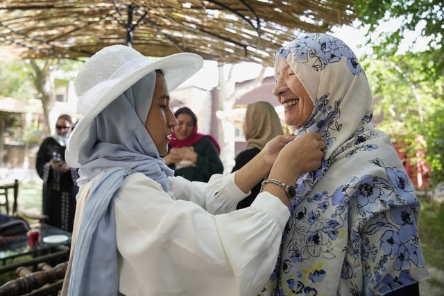 Maryam, a young Afghan on her first day of training to become a tour guide, helps 82-year-old Australian tourist Suzanne Sandral adjust her hijab in Kabul, Afghanistan, Wednesday, May 28, 2025. (AP Photo/Ebrahim Noroozi)