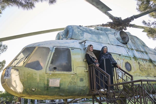 Afghan tour guide Somaya Moniry, 24, left, and 82-year-old Australian tourist Suzanne Sandral pose for a photo next to a military helicopter during a visit to the War Museum in Kabul, Afghanistan, Wednesday, May 28, 2025. (AP Photo/Ebrahim Noroozi)